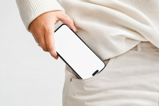 Modern smartphone mockup in back pocket of white jeans held by hand, blank mobile screen template for app presentation, digital lifestyle, technology concept, mobile advertising and branding