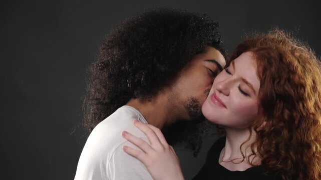 Romantic interracial couple sharing an affectionate kiss, symbolizing love and connection. This intimate moment between diverse partners is captured in a studio setting, highlighting their tender emot