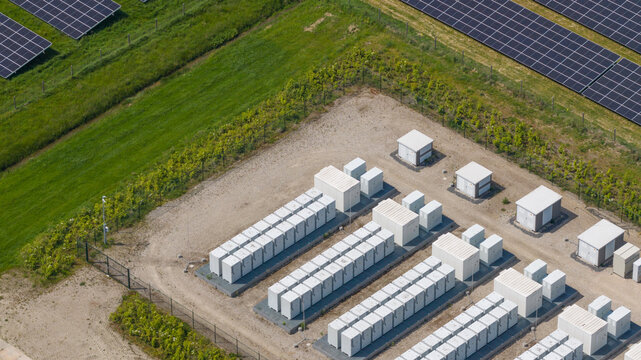 Aerial view of a solar farm and battery energy storage system with white container units and solar panels on a sunny day in Wanneperveen, Overijssel, Netherlands.
