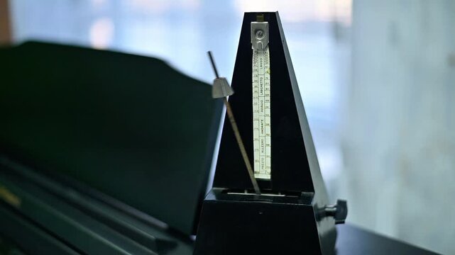Piano with mechanical metronome, pendulum in motion. Focus on tempo device and piano keys, music practice, rhythm and instrument concept, closeup detail, indoor environment.