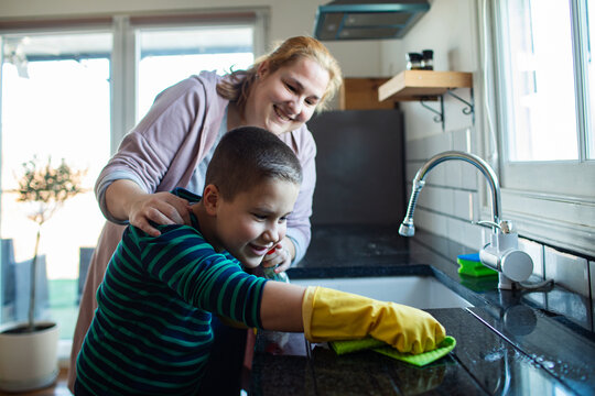 Parent and child cleaning kitchen countertop at home