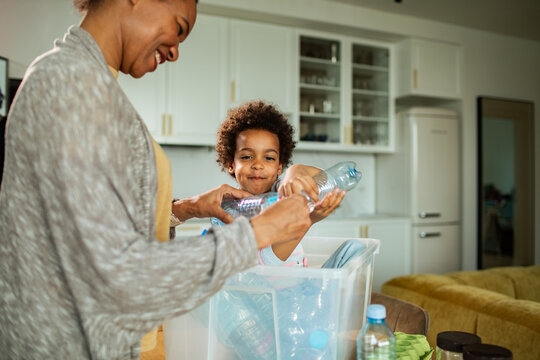 Parent and child recycling plastic bottles in home kitchen