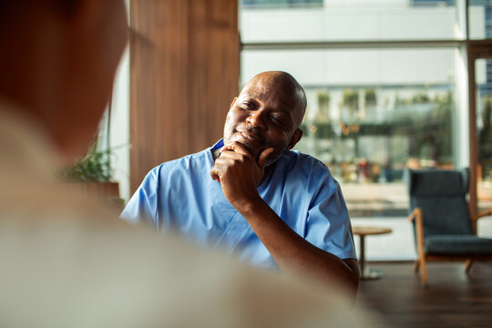Senior male nurse listening to patient in modern clinic