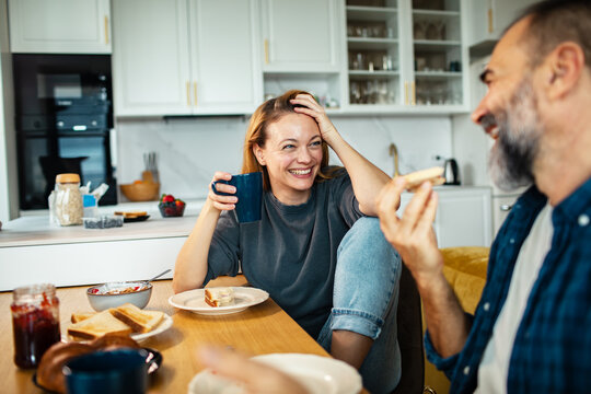 Smiling couple having breakfast at home kitchen