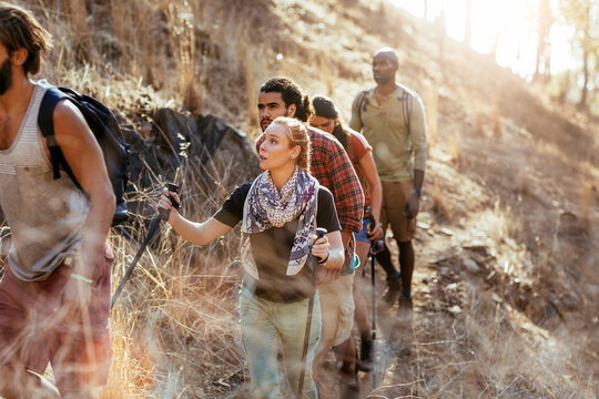 Friends hiking with trekking poles on a dry hillside trail