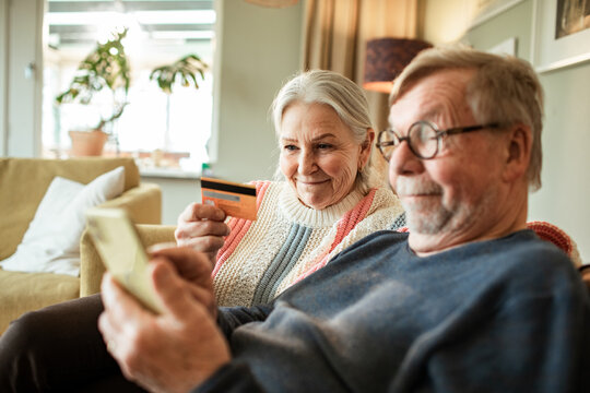 Senior couple shopping online at home with credit card and smartphone
