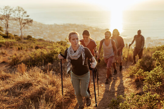 Group of friends hiking coastal trail at sunset
