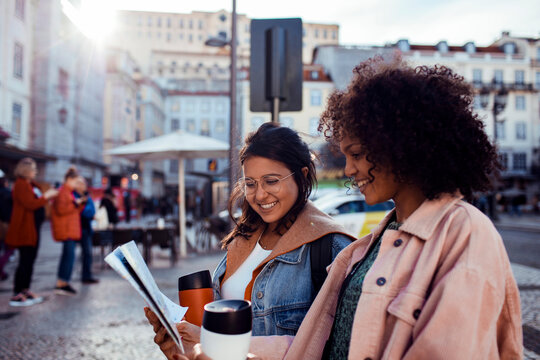 Two friends reading a city map in a european old town