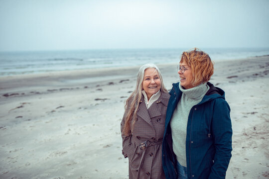 Two senior women walking and smiling on a foggy beach