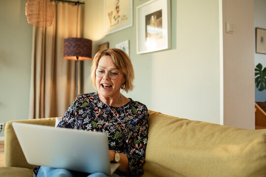 Smiling senior woman video calling on laptop in living room
