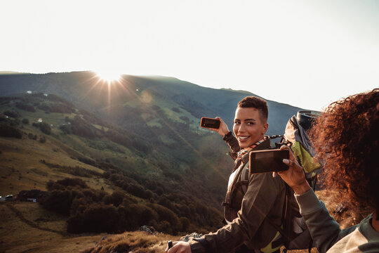 Two hikers using smartphones at sunrise in the mountains