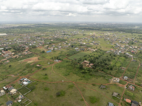 Aerial view of sprawling residential developments and green fields under a cloudy sky in Thika, Kiambu County, Kenya.