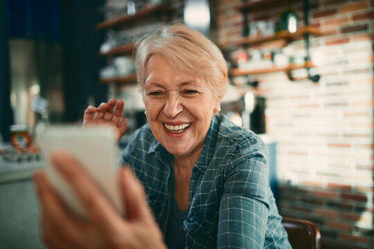 Smiling senior woman video calling in home kitchen