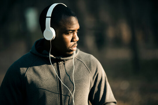 Man in hoodie listening to music with headphones on a forest trail