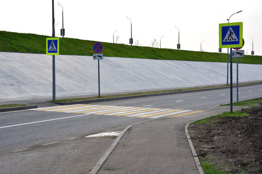 Pedestrian crossing on an empty road with concrete wall and green grass no people