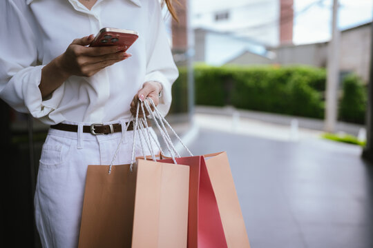 Close-up of a shopper carrying colorful shopping bags outdoors, symbolizing retail spending, consumer lifestyle, fashion purchases, and modern shopping experiences.