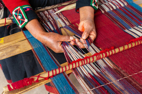 Close up of artisan hands weaving colorful threads on traditional Peruvian loom