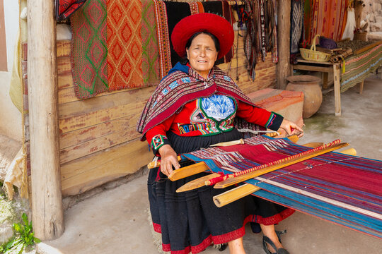Peruvian woman weaving colorful textile on traditional wooden loom in artisan workshop