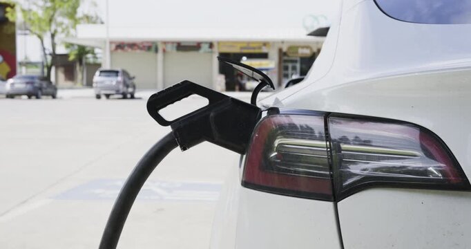 Casual woman use outdoor station EV car charge with mobile phone transport technology