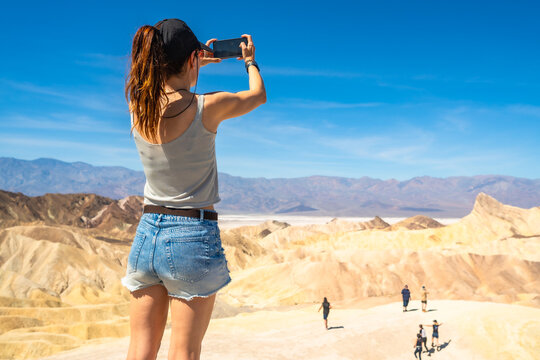 Woman capturing desert landscape at zabriskie point with phone