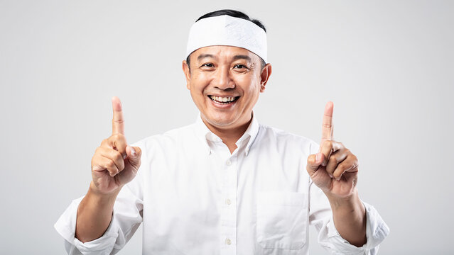 Cheerful Balinese man wearing Indonesian traditional udeng giving thumbs up finger gesture.