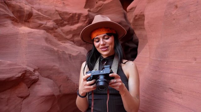 Cheerful female traveler and photographer with a professional camera admiring the stunning rock formations while exploring the famous antelope canyon, a slot canyon in page, arizona