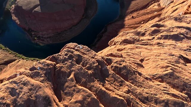 Point of view of a man walking towards the edge of a cliff overlooking the iconic horseshoe bend, revealing the stunning colorado river landscape in page, arizona, on a sunny day