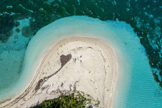 Aerial view of Yasawa Island featuring a curved white sand beach, vibrant turquoise coral reef, and crystal clear ocean water in Nadi, Western Division, Fiji.