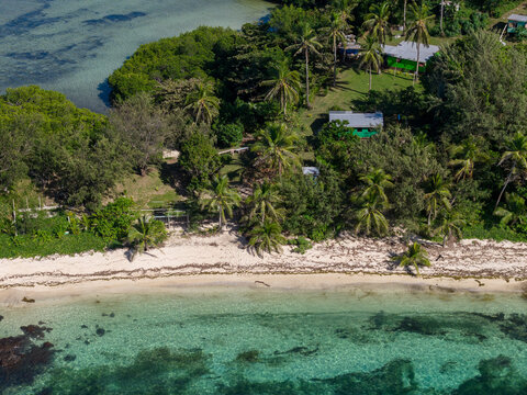 Aerial view of Yasawa Island featuring a white sand beach, lush palm trees, and turquoise waters with small coastal buildings in Nadi, Western Division, Fiji.