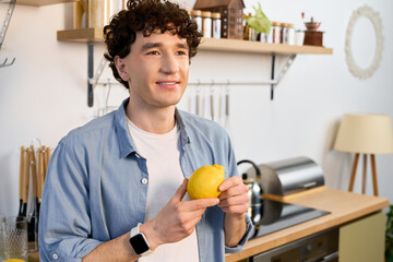 Fototapeta premium Young man enjoys a moment of bliss in his modern apartment while holding a lemon