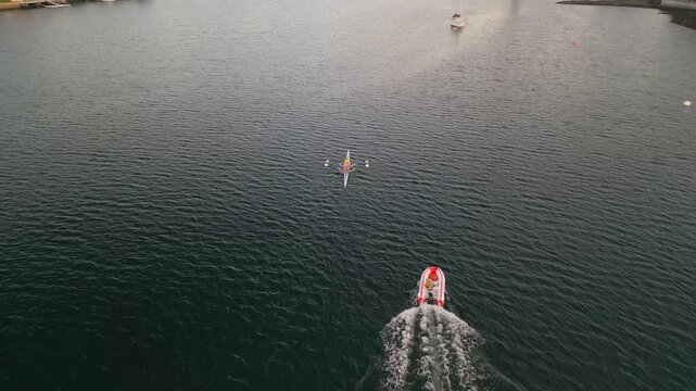 Young women paddle fiercely in a two-seater rowing boat as they navigate the peaceful waters of Halifax Ocean Bay, showcasing teamwork and athleticism