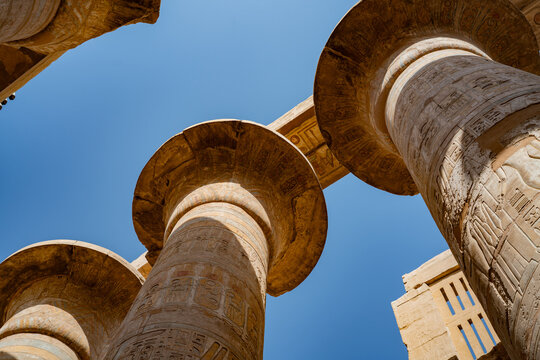 Epic Karnak temple ancient Egyptian architecture hypostyle hall panorama. 
Cinematic low angle view of historic Luxor sandstone columns, 
carved pharaoh hieroglyphs bas relief and blue sky.
