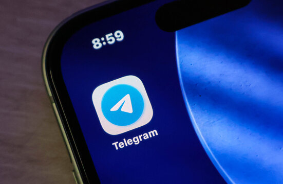 Closeup of the telegram mobile application icon displayed on an iphone screen with a blue background