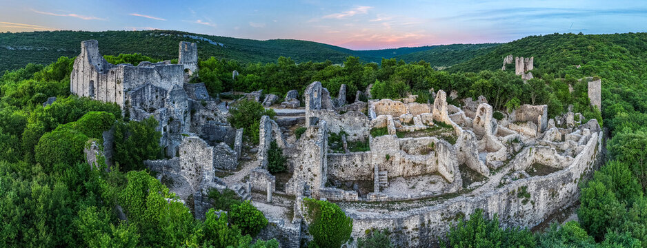 Aerial view of the Dvigrad ruins, an abandoned medieval town nestled among lush green forests and rolling hills under a soft sunset sky in Kanfanar, Istria County, Croatia.