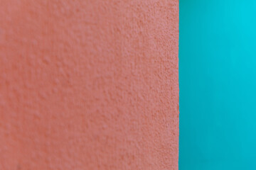 Fototapeta premium Abstract view of a textured orange wall meeting a smooth cyan background. Minimalist design, architectural detail, color contrast.