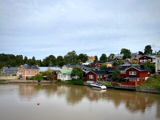 Obraz premium Porvoo, Finland is depicted with its charming riverside houses featuring traditional red wooden facades and some pastel-colored buildings. The serene river reflects the homes and scattered docks