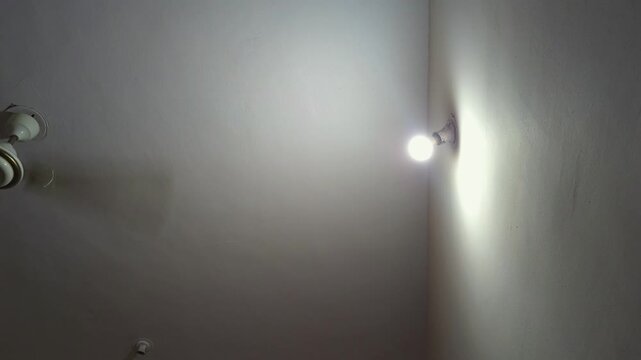 A solitary bulb illuminates a spinning ceiling fan in a dark, empty room. Captures themes of domestic isolation, depression, mental health struggles, & the quiet loneliness of modern apartment living.