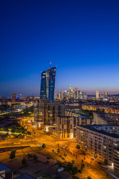 Aerial view of the ECB Tower and the illuminated city skyline during blue hour in Frankfurt am Main, Hessen, Germany.