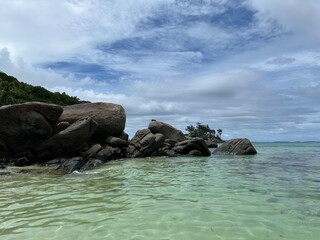 Obraz premium A beautiful beach on a cloudy day. Beautiful large boulders and ocean waves. The pristine nature of the Seychelles