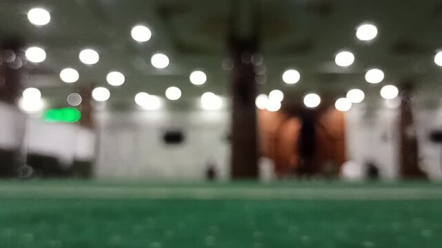 Artistic blur and defocus view inside a mosque during Maghrib prayer time, creating a peaceful spiritual atmosphere with soft evening lighting.