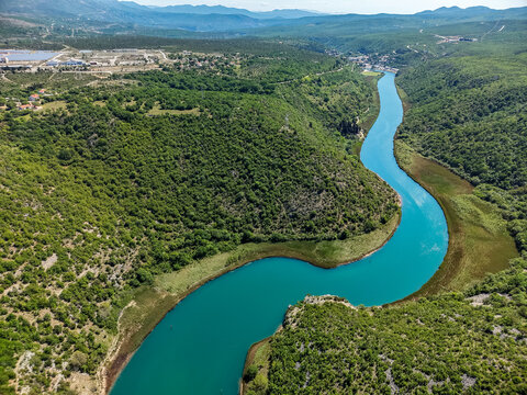 Aerial view of the winding Zrmanja River flowing through a lush green canyon near the Suncana elektrana Obrovac solar plant Zaton Obrovacki, Zadar County, Croatia.