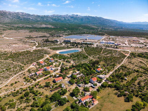 Aerial view of Suncana elektrana Obrovac solar power plant and the village of Zaton Obrovacki with rugged mountains and green fields Zaton Obrovacki, Zadar County, Croatia.