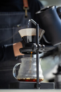 Barista pouring hot water from kettle for v60 drip coffee