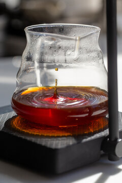 Single coffee drop splashing into clear glass server with ripples