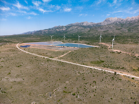 Aerial view of Suncana elektrana Obrovac solar farm and wind turbines in a rocky landscape under a blue sky Zaton Obrovacki, Zadar County, Croatia.