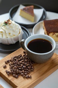Black coffee in cup with roasted coffee beans and desserts
