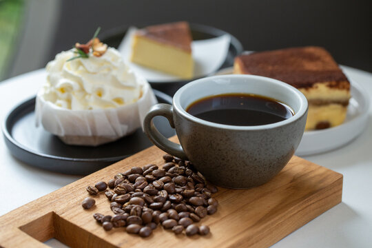 Hot black coffee mug with roasted beans and sweet bakery