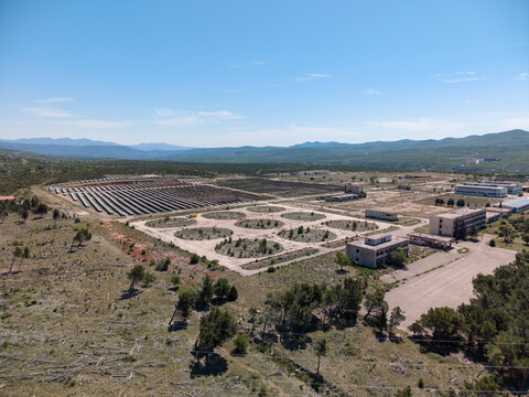 Aerial view of Suncana elektrana Obrovac solar power plant with rows of photovoltaic panels and industrial buildings under a clear blue sky in Zaton Obrovacki, Zadar County, Croatia.