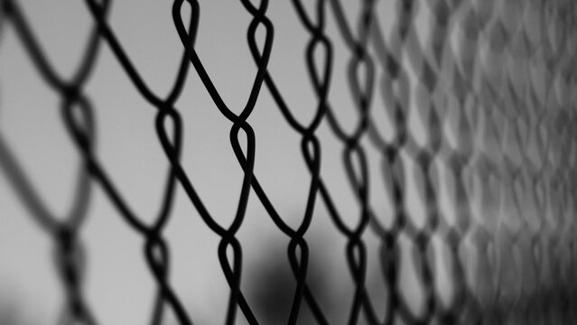 Close up of a metallic chain link fence. Background texture of a silver wire mesh fencing structure outdoors. Conceptual industrial pattern of steel security barrier and boundary grid.
