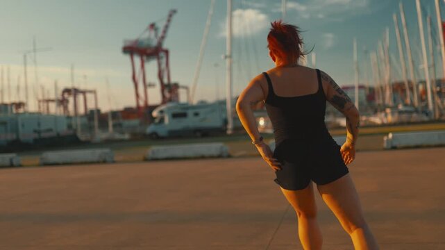 Tattooed woman roller skating during sunset at the marina